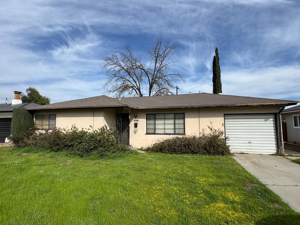 ranch-style house featuring a garage, a front yard, driveway, and stucco siding