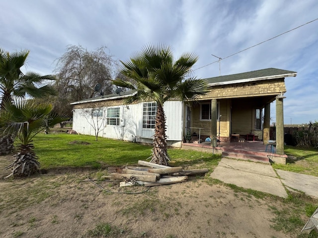 rear view of property featuring covered porch and a lawn