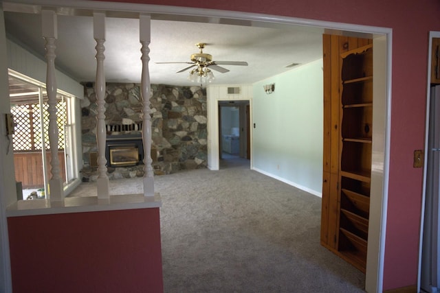 unfurnished living room featuring visible vents, ceiling fan, carpet flooring, and a wood stove