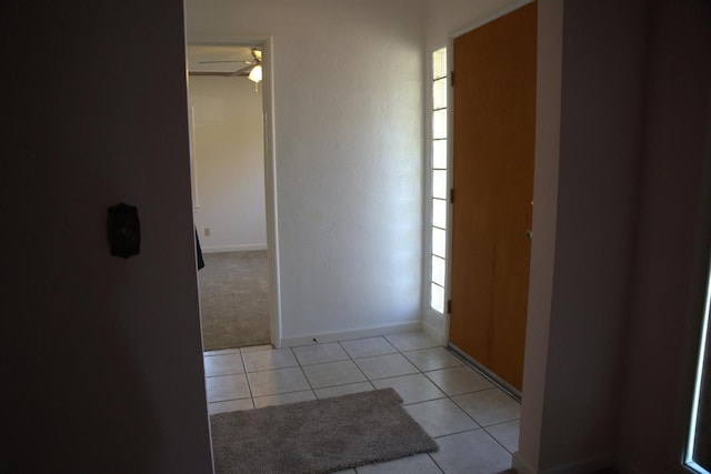 corridor with light colored carpet, baseboards, and light tile patterned floors