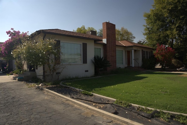 view of home's exterior featuring crawl space, a lawn, a chimney, and stucco siding