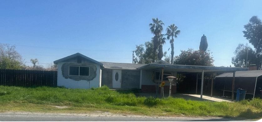 ranch-style home with driveway, an attached carport, and fence