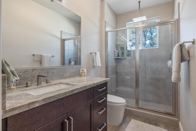 full bath featuring a stall shower, vanity, and toilet