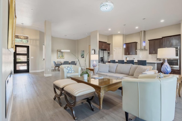 living room with light wood-style floors, recessed lighting, a towering ceiling, and baseboards