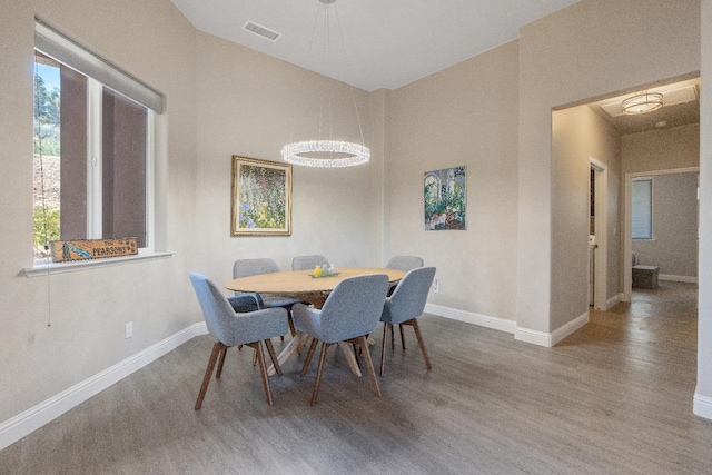 dining space featuring a high ceiling, visible vents, baseboards, and wood finished floors