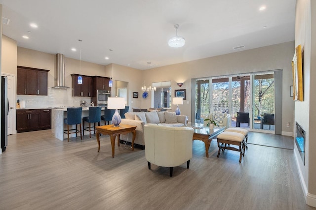 living room with recessed lighting, visible vents, light wood-style floors, a chandelier, and baseboards