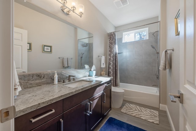 bathroom with visible vents, toilet, shower / bath combo with shower curtain, vanity, and wood finished floors