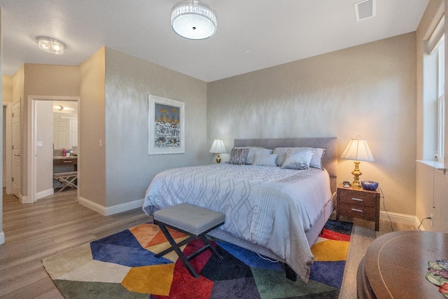 bedroom with baseboards, visible vents, and wood finished floors