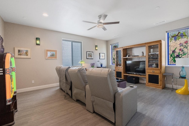 living room featuring a ceiling fan, visible vents, baseboards, and wood finished floors