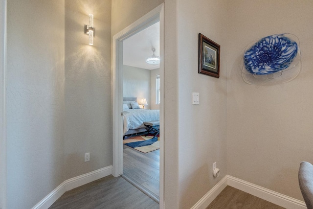 corridor featuring baseboards and wood finished floors