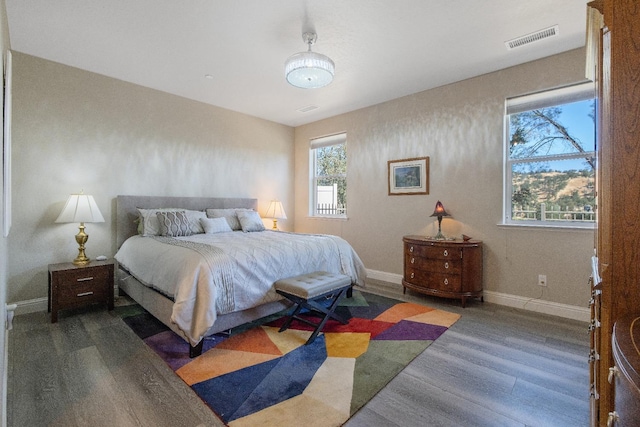 bedroom featuring baseboards, visible vents, and wood finished floors