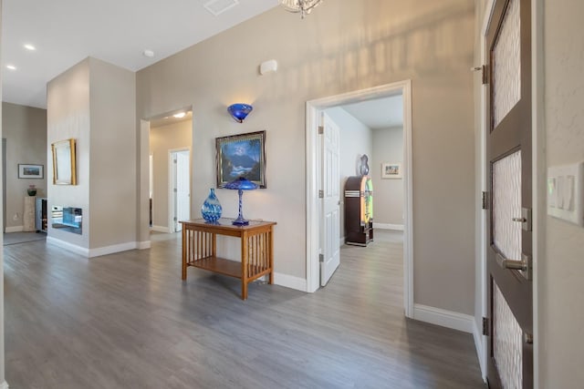 corridor with a towering ceiling, visible vents, baseboards, and wood finished floors