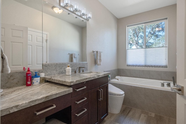 bathroom featuring toilet, a garden tub, and vanity