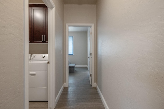 hallway featuring a textured wall, wood finished floors, washer / dryer, and baseboards