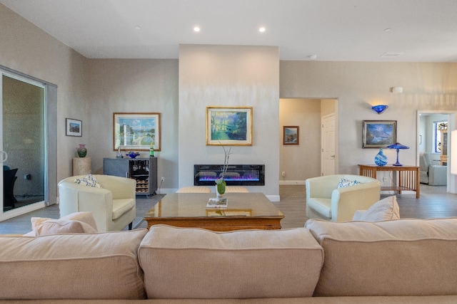 living area featuring recessed lighting, a glass covered fireplace, and baseboards