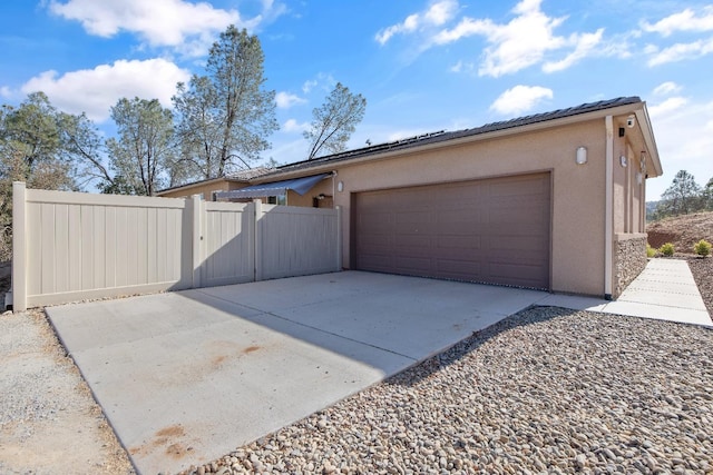 garage with concrete driveway and fence