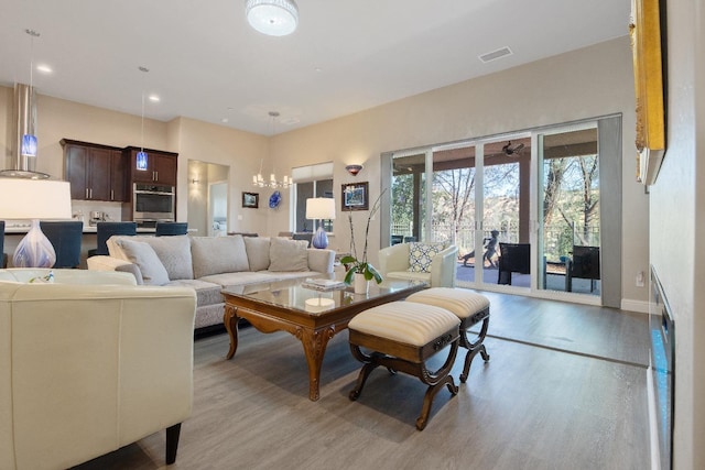 living room with light wood-type flooring, visible vents, a notable chandelier, and recessed lighting