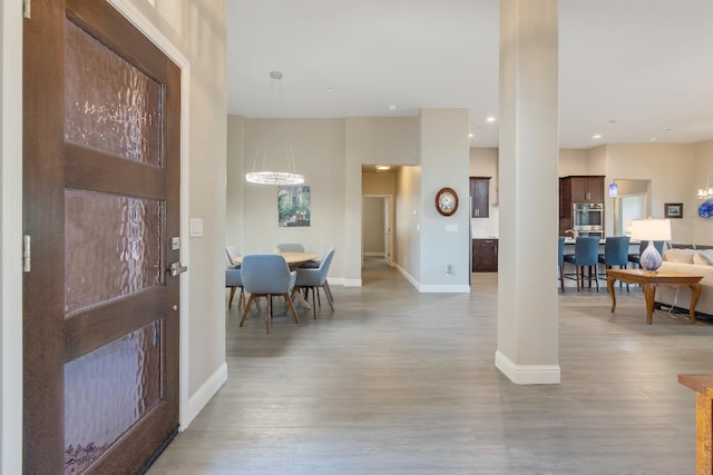 foyer entrance with an inviting chandelier, baseboards, wood finished floors, and recessed lighting