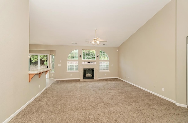 unfurnished living room with ceiling fan, lofted ceiling, light colored carpet, a fireplace, and baseboards