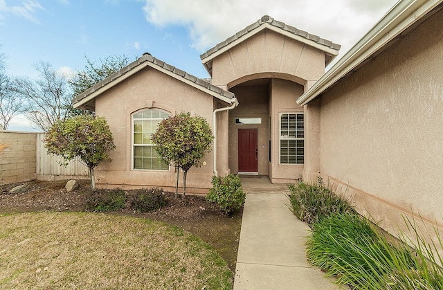 property entrance with fence and stucco siding