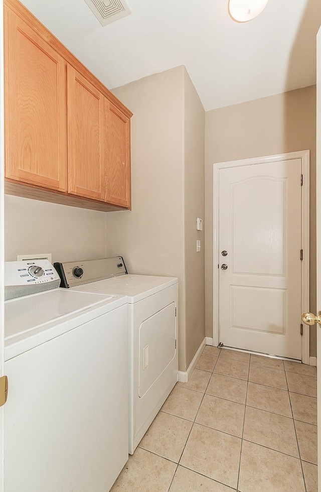 washroom with washing machine and clothes dryer, light tile patterned floors, cabinet space, visible vents, and baseboards