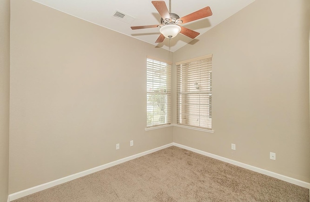 carpeted spare room with a ceiling fan, visible vents, vaulted ceiling, and baseboards