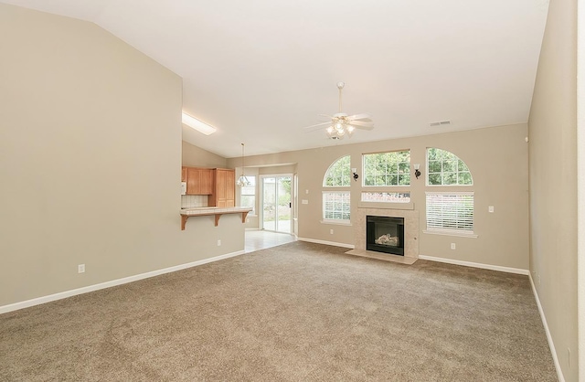 unfurnished living room with ceiling fan, lofted ceiling, a tile fireplace, carpet flooring, and visible vents