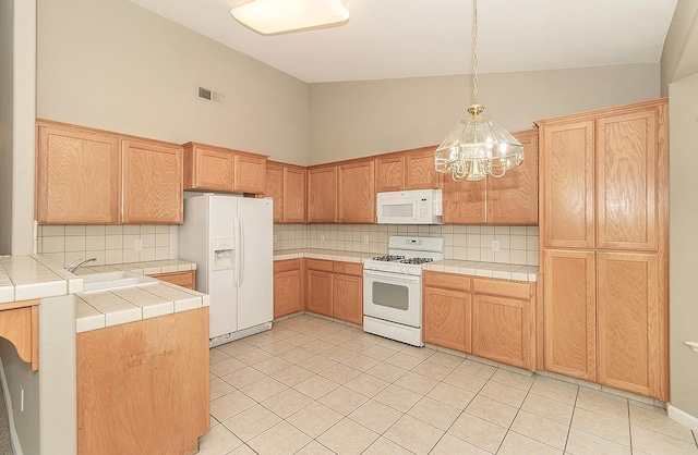 kitchen featuring white appliances, visible vents, tile countertops, and decorative backsplash