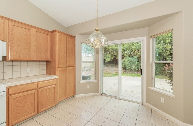 kitchen with tile countertops, plenty of natural light, vaulted ceiling, and backsplash