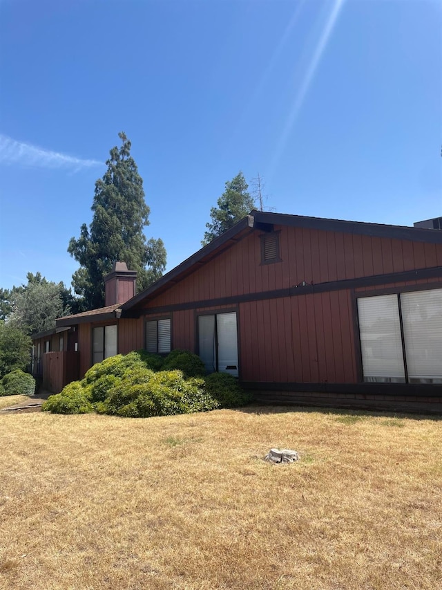 view of side of property featuring a chimney and a yard