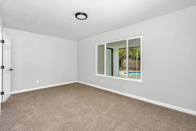 carpeted spare room featuring baseboards