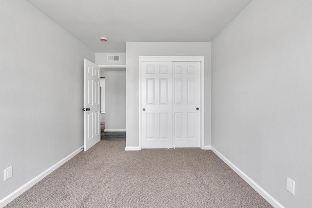 unfurnished bedroom with carpet floors, baseboards, visible vents, and a closet