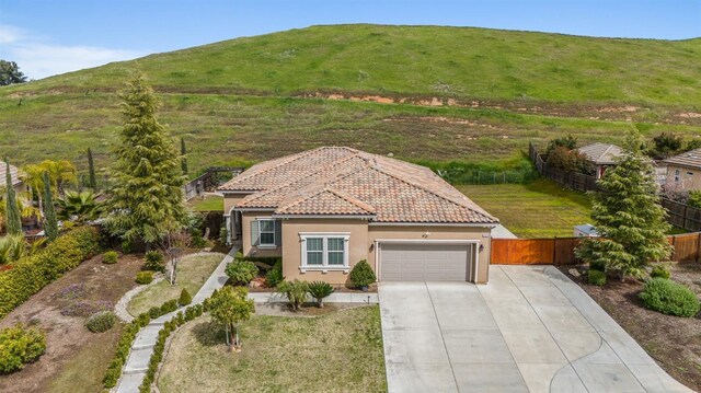 exterior space with a tile roof, an attached garage, driveway, stucco siding, and fence