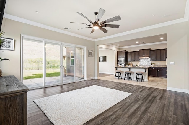 living area featuring a ceiling fan, light wood-type flooring, visible vents, and baseboards