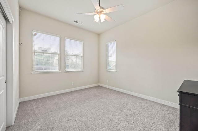 carpeted empty room with a ceiling fan, visible vents, and baseboards