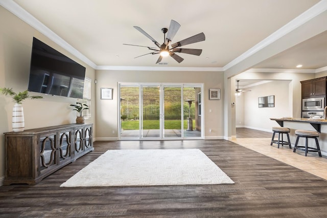 living area with ornamental molding, a ceiling fan, wood finished floors, and baseboards