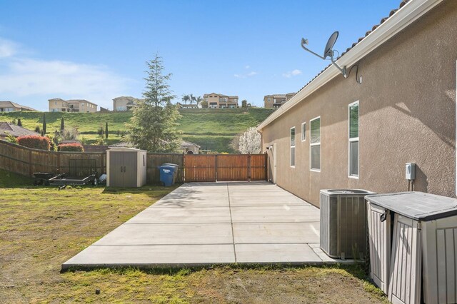 view of patio featuring an outdoor structure, central AC unit, a shed, and a fenced backyard