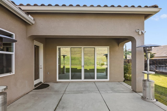 entrance to property featuring stucco siding, fence, and a patio area