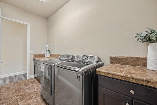 clothes washing area with cabinet space, baseboards, and separate washer and dryer