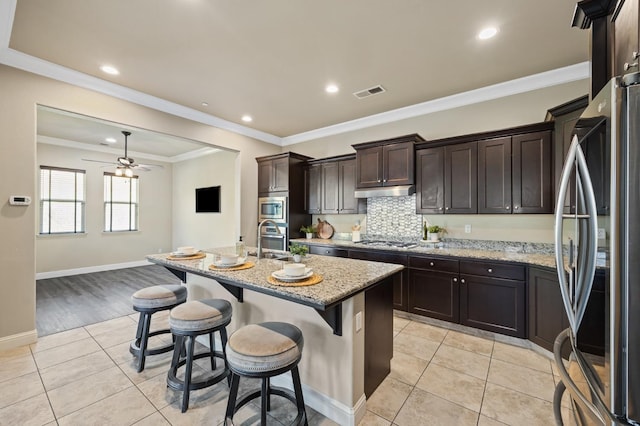 kitchen with appliances with stainless steel finishes, light tile patterned flooring, visible vents, and light stone counters