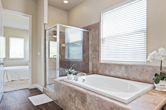 bathroom featuring wood finished floors, a garden tub, ensuite bath, and a stall shower