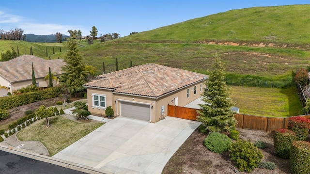 view of front of house featuring stucco siding, concrete driveway, fence, a garage, and a tiled roof