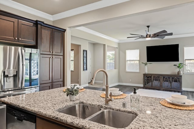 kitchen with a sink, stainless steel appliances, dark brown cabinets, open floor plan, and ornamental molding