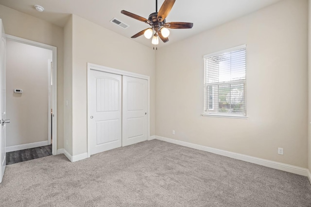 unfurnished bedroom with carpet flooring, a closet, a ceiling fan, visible vents, and baseboards