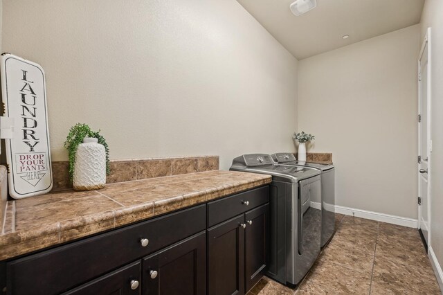 clothes washing area featuring cabinet space, light tile patterned floors, baseboards, and separate washer and dryer