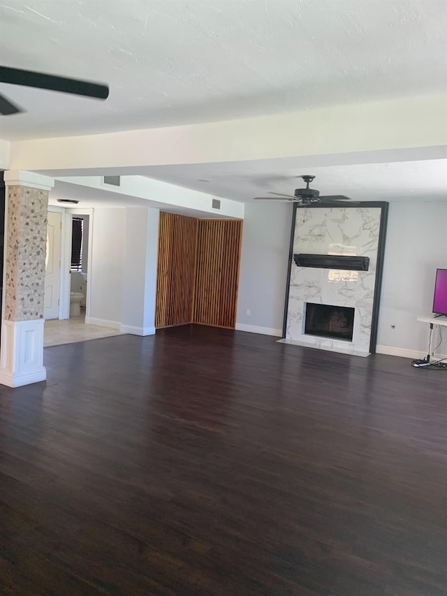 unfurnished living room featuring ceiling fan, visible vents, wood finished floors, and a high end fireplace