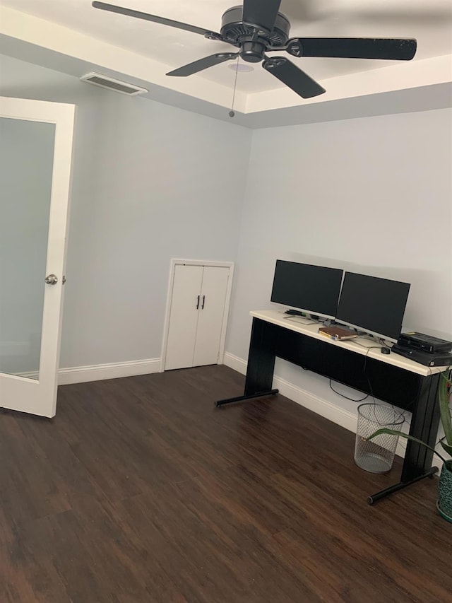 office area with a raised ceiling, visible vents, a ceiling fan, wood finished floors, and baseboards