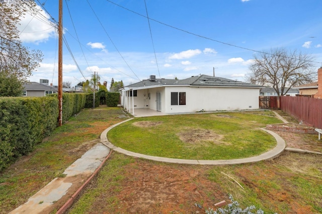 rear view of property with a fenced backyard, a patio area, a lawn, and stucco siding