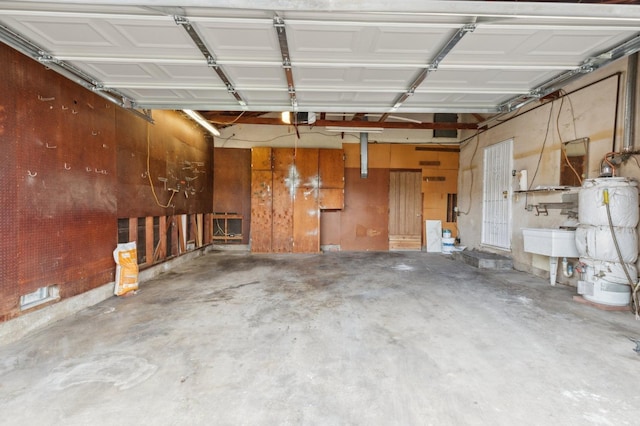 garage with gas water heater, a garage door opener, and a sink