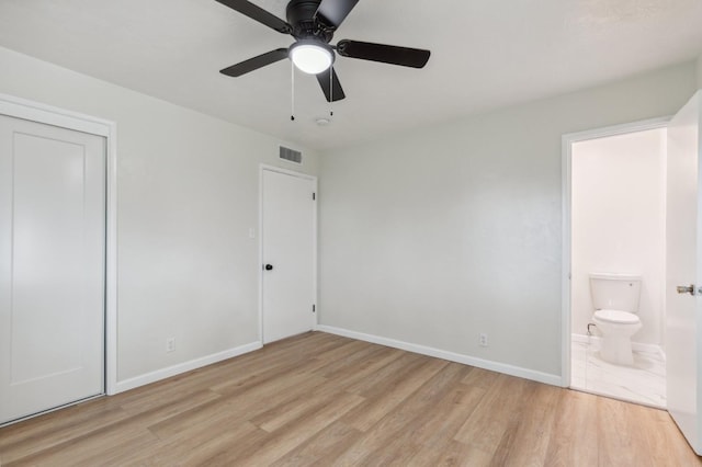 unfurnished bedroom featuring a closet, connected bathroom, light wood-style flooring, baseboards, and visible vents